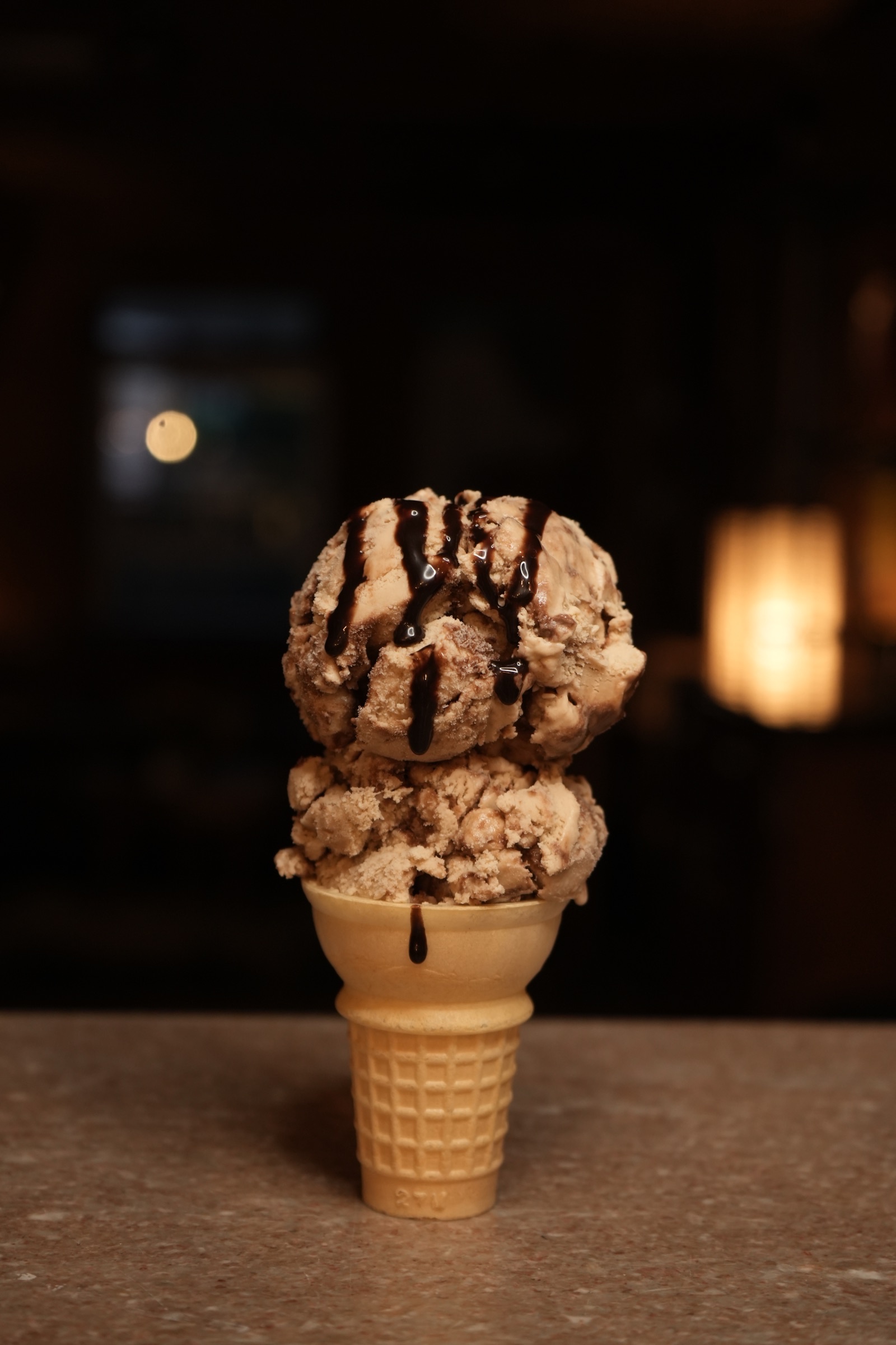 Two scoops of ice cream in a cone with chocolate drizzle
